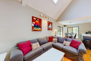 ein Wohnzimmer mit einer grauen Couch und bunten Kissen in der Unterkunft Tree Top Oasis in Truro