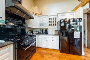 a kitchen with white cabinets and a black refrigerator at Paradise On Cape Cod in Orleans