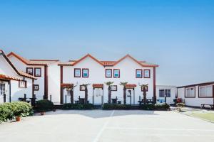 a large white building with palm trees in a parking lot at Moon Rabbit Pension in Jeju