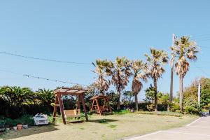 a playground with a swing set and palm trees at Moon Rabbit Pension in Jeju