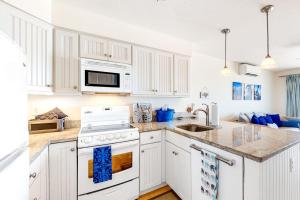 a kitchen with white cabinets and a white stove top oven at Nautical Haven at Seaside in North Truro