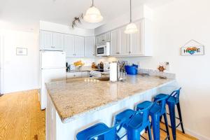a kitchen with white cabinets and blue stools at Nautical Haven at Seaside in North Truro +14 photos