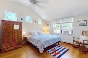 a bedroom with a bed and a chair and windows at esCAPE in Eastham