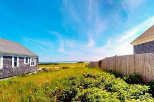 a house and a fence next to a field at Anchorage Escape in Truro