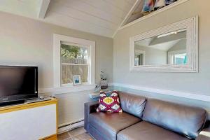 a living room with a leather couch and a flat screen tv at Anchorage Escape in Truro