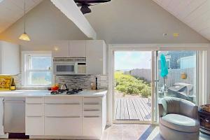a kitchen with white cabinets and a large window at Anchorage Escape in Truro