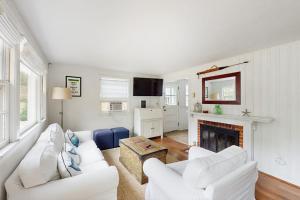 a living room with two white couches and a fireplace at The Kettle Cottage in Cotuit