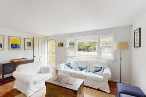 a living room with two white couches and a table at The Kettle Cottage in Cotuit