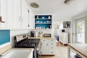 a kitchen with white cabinets and a stove at The Kettle Cottage in Cotuit +24 photos