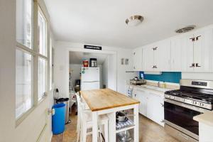 a kitchen with white cabinets and a wooden table at The Kettle Cottage in Cotuit