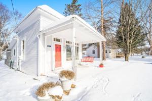 a white house with a red door in the snow at Lake Daze in Boyne City