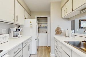 a kitchen with white cabinets and a white refrigerator at Wilderness 9 in Glen Arbor +10 photos