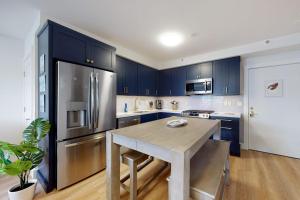 a kitchen with blue cabinets and a stainless steel refrigerator at Villa Balena - A Cape Cod Oasis in Dennis Port