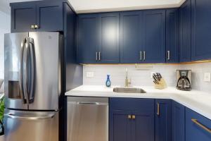 a kitchen with blue cabinets and a stainless steel refrigerator at Villa Balena - A Cape Cod Oasis in Dennis Port +18 photos