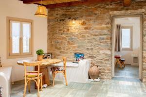 a room with a stone wall and a table and chairs at Heliopetra Punta in Ios Chora +103 photos