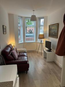 a living room with a leather couch and a television at Queens apartments Belfast in Belfast
