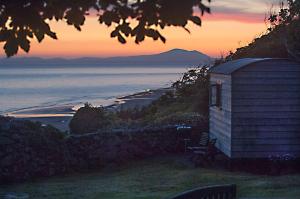 a building on a hill with a view of the ocean at The Farm Hut in Barmouth