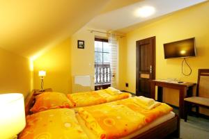 two beds in a hotel room with yellow walls at Penzion Veronika in Belá