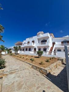 a large white building with a pathway in front of it at AVRA Apartments & Studios in Frý