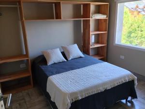a bedroom with a bed and shelves and a window at Cabaña con costa de arroyo in San Martín de los Andes