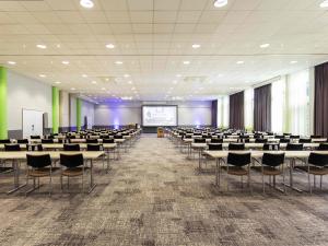 a conference room with tables and chairs and a screen at Novotel Düsseldorf City West in Düsseldorf
