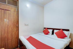 a bedroom with a bed with red and white pillows at Hotel O Ratiram in Kalkaji Devi