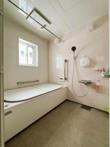 a bathroom with a large white room with a shower at ゲストハウスさちさんち in Wagō