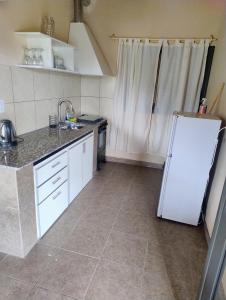 a kitchen with a white refrigerator and a tile floor at FiNCA DACA in Junín +6 photos