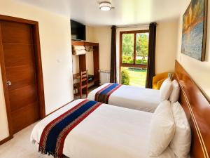 a hotel room with two beds and a window at Hotel Sol Natura in Ollantaytambo