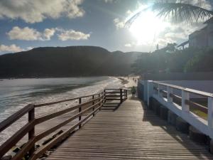ein Holzsteg, der zu einem Strand mit Sonne führt in der Unterkunft Casa Dunas in Florianópolis