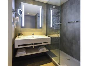 a bathroom with a sink and a mirror and a shower at Novotel Szczecin Centrum in Szczecin +134 photos