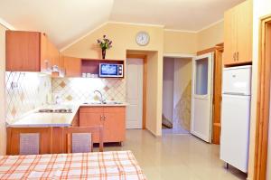 a kitchen with wooden cabinets and a white refrigerator at Holiday Home Rose in Hajdúszoboszló +7 photos