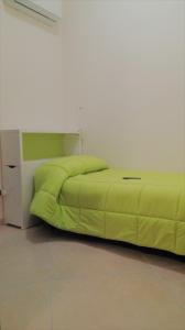 un grande letto verde in una stanza bianca di Incontro Montoro Guest House & Restaurant a Montoro Inferiore