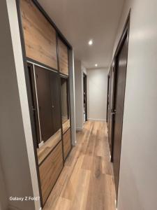 a hallway with wooden floors and sliding glass doors at JOLYKa résidence avec caméra et digicode possibilité location voiture Mercedes, garage ,climatisation ,cheminée, Netflix, petit déjeuner ,repas du soir fondue, raclette, barbecue sur demande in Albertville