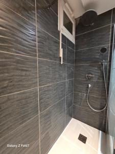 a bathroom with a shower with gray tiles at JOLYKa résidence avec caméra et digicode possibilité location voiture Mercedes, garage ,climatisation ,cheminée, Netflix, petit déjeuner ,repas du soir fondue, raclette, barbecue sur demande in Albertville