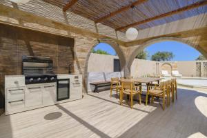 an outdoor kitchen and dining area with a table and chairs at Villa Lavender by Villa Plus in Kolymbia