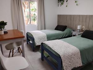 a room with two beds and a table and a desk at Casa Esmeralda in Concordia