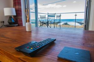 une télécommande assise au-dessus d'une table en bois dans l'établissement Farneholm Annex Cottage, à Beadnell