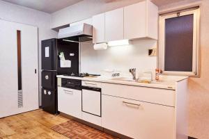 a kitchen with white cabinets and a black refrigerator at Kvillage BLDG 無料駐車場付き 原爆ドームまで徒歩15分 大人数でもOK in Hiroshima +43 photos
