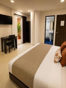 a hotel room with a bed and a desk and a bathroom at Raí home in Medellín