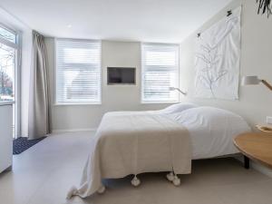 a white bedroom with a large bed and windows at Duinsuite in Oostkapelle