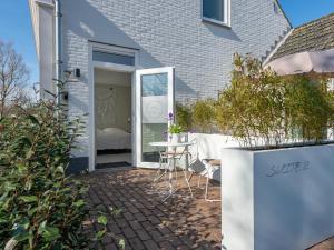 a patio with a table and chairs in front of a house at Duinsuite in Oostkapelle