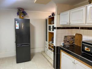 a kitchen with a black refrigerator and white cabinets at Villa Sais avec piscine in Meknès