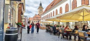 a group of people walking down a street with tables and chairs at Modest Ultra Central Apartment Council Square in Braşov +6 photos