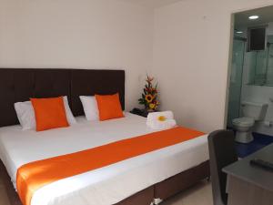 a bedroom with a large bed with orange and white pillows at Raí home in Medellín +3 photos