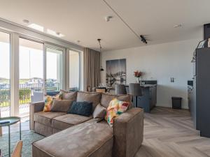 a living room with a couch and a kitchen with windows at De Havenkamer in Kamperland