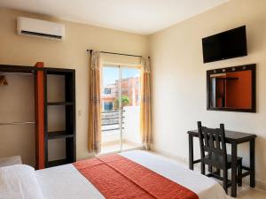 a bedroom with a bed and a desk and a window at Hotel Valle del Huajucar in Calvillo
