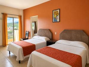 a hotel room with two beds and a balcony at Hotel Valle del Huajucar in Calvillo