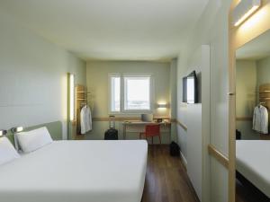 a room with a bed and a desk and a window at Ibis Budget Málaga Aeropuerto Avenida de Velazquez in Málaga