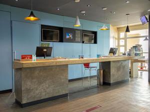 eine große Lobby mit einer großen Holztheke und Stühlen in der Unterkunft ibis Macae in Macaé